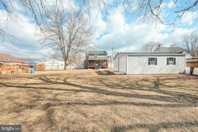 back of property with a yard, fence, and an outdoor structure