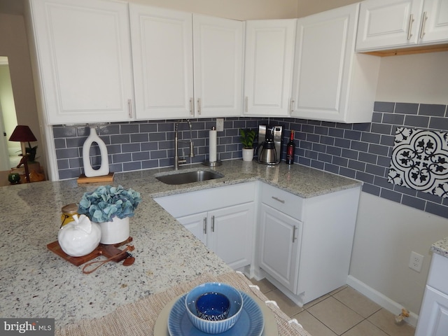 kitchen with tasteful backsplash, light stone counters, white cabinets, and light tile patterned flooring