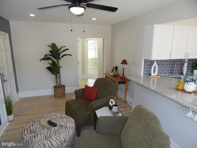 living area with recessed lighting, ceiling fan, light wood-style flooring, and baseboards