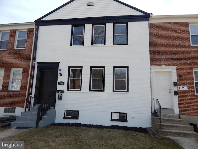 townhome / multi-family property featuring entry steps, a front lawn, and brick siding