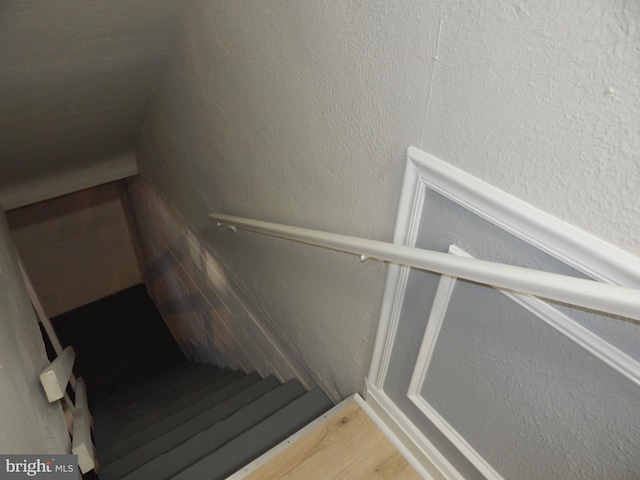 stairway with a textured wall and wood finished floors