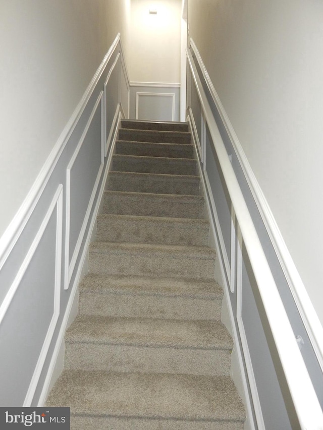 staircase with wainscoting and a decorative wall