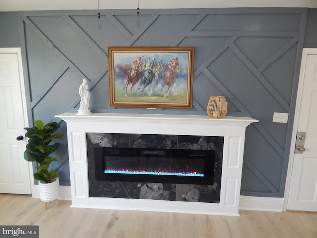 details with a glass covered fireplace, a decorative wall, and wood finished floors