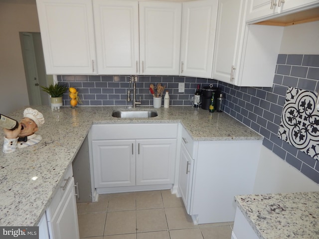 kitchen with tasteful backsplash, light stone counters, and a sink