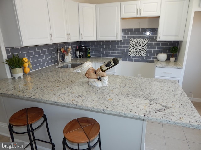 kitchen featuring light stone counters, white cabinetry, and a kitchen breakfast bar