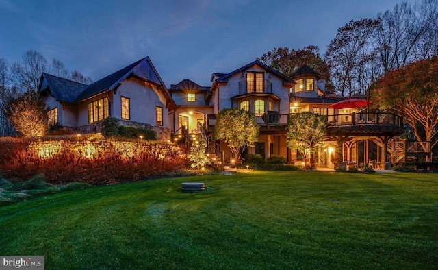 rear view of property featuring a lawn and stucco siding