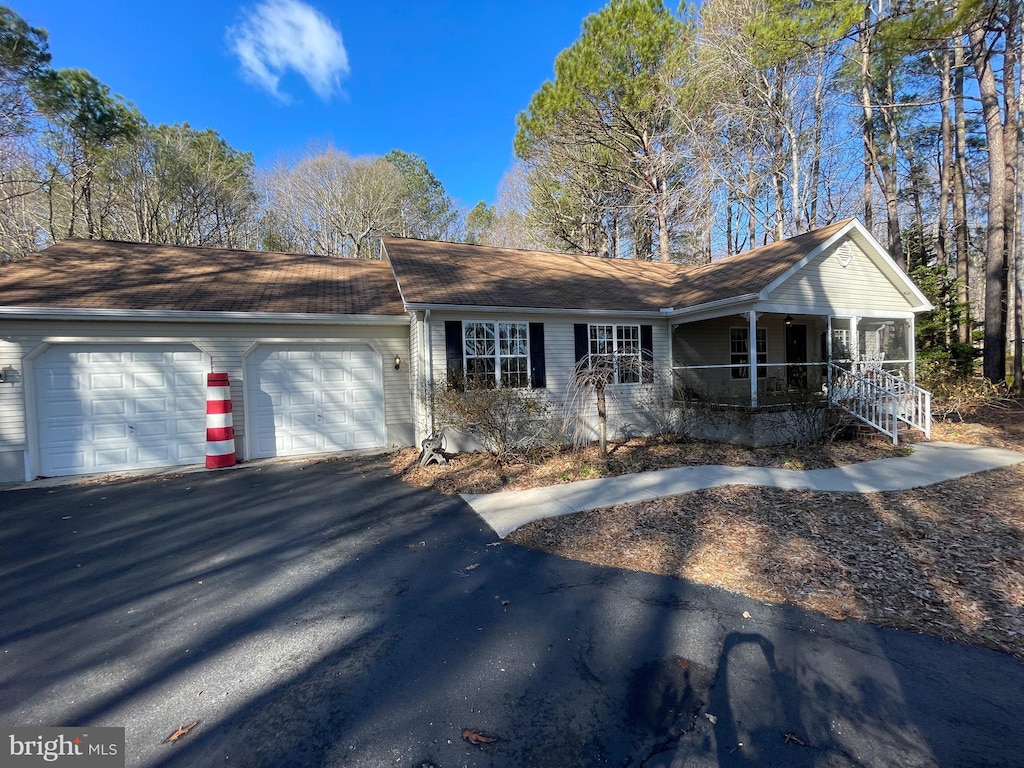 single story home featuring covered porch, aphalt driveway, and an attached garage