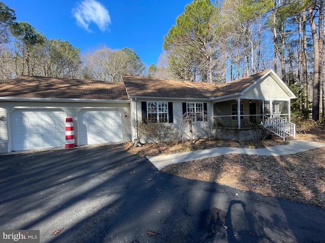 single story home featuring covered porch, aphalt driveway, and an attached garage