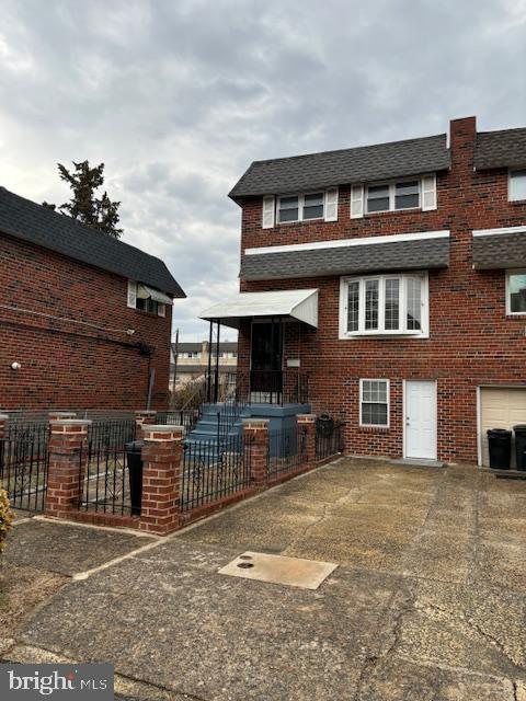 view of front of house featuring driveway, fence, and brick siding