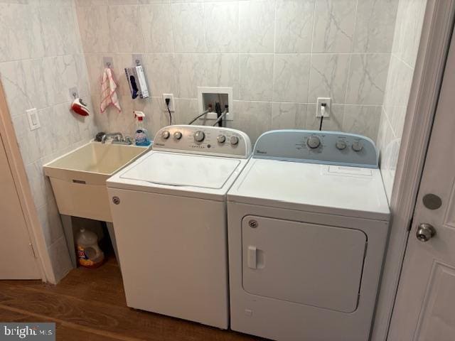 clothes washing area with laundry area, independent washer and dryer, wood finished floors, and tile walls