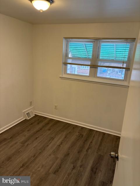 unfurnished room with dark wood-style floors, plenty of natural light, and baseboards