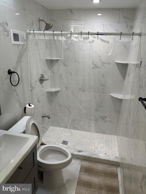 bathroom with toilet, vanity, visible vents, marble finish floor, and a marble finish shower