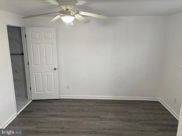 spare room featuring dark wood-type flooring, ceiling fan, and baseboards