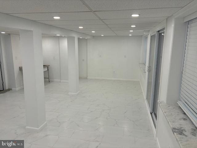 finished below grade area with marble finish floor, recessed lighting, a paneled ceiling, and baseboards