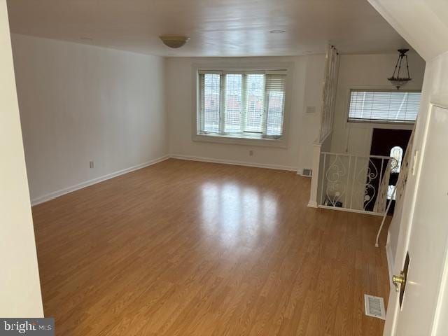 unfurnished living room with light wood-style flooring, visible vents, and baseboards