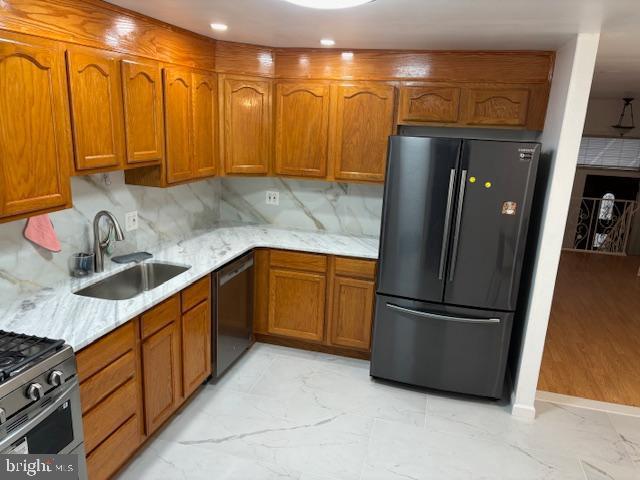 kitchen with freestanding refrigerator, marble finish floor, dishwasher, and a sink