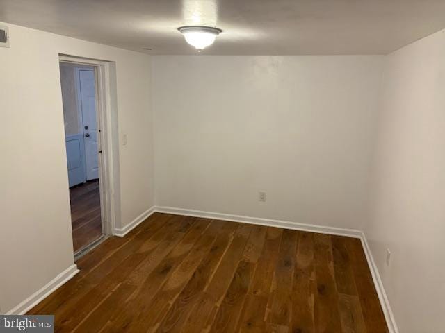 empty room with visible vents, baseboards, and dark wood-style flooring