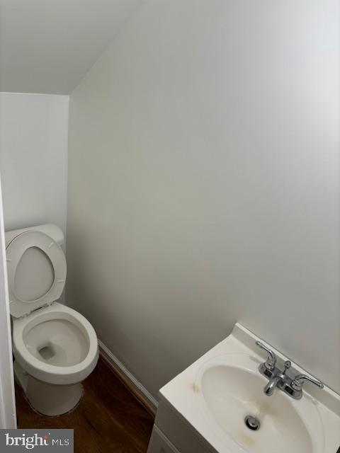 bathroom with wood finished floors, vanity, toilet, and baseboards