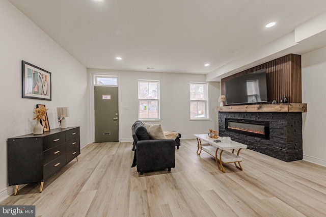 living area featuring recessed lighting, baseboards, a fireplace, and light wood finished floors