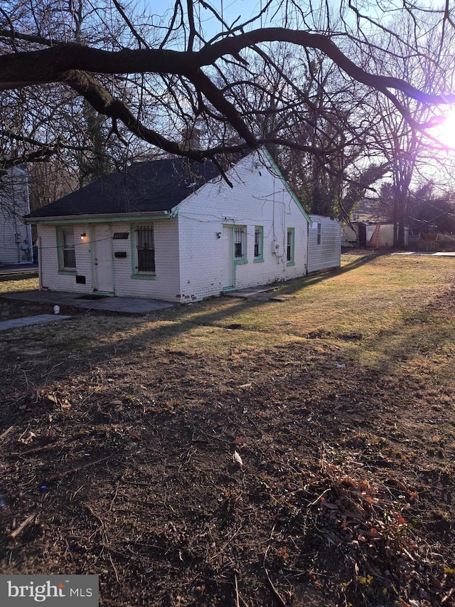 view of front of property featuring a patio, brick siding, and a front yard