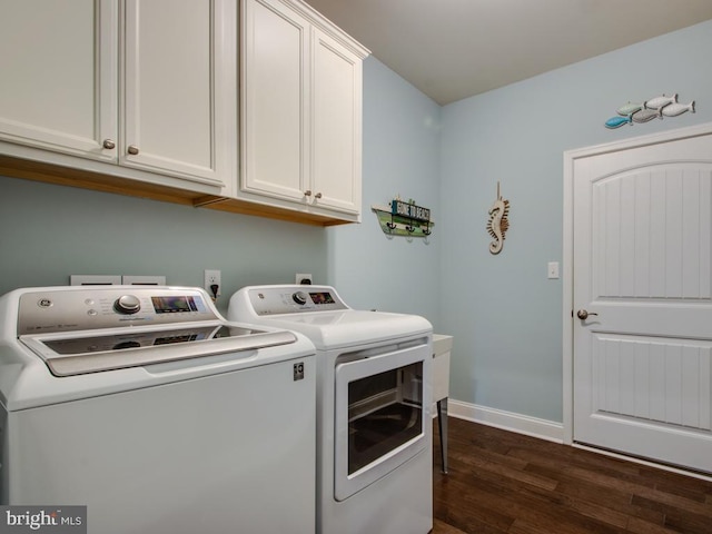 washroom featuring cabinet space, baseboards, separate washer and dryer, and dark wood finished floors