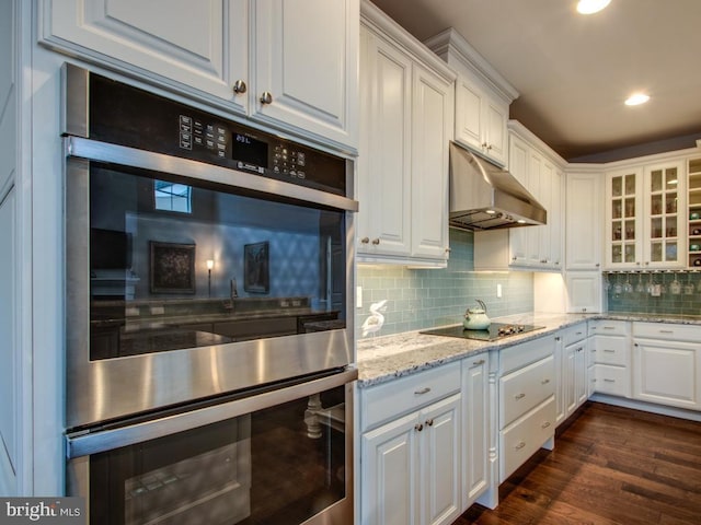 kitchen featuring stainless steel double oven, backsplash, white cabinetry, and under cabinet range hood