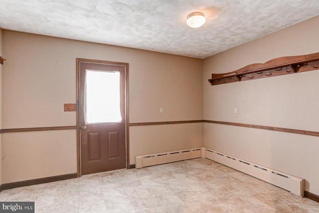 spare room with baseboards, baseboard heating, and a textured ceiling