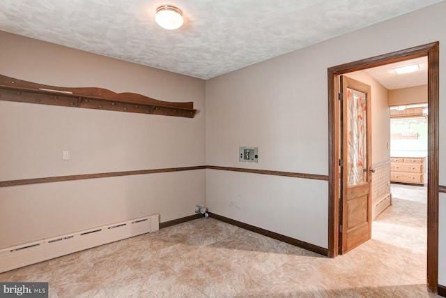 spare room featuring baseboards, a baseboard heating unit, and a textured ceiling