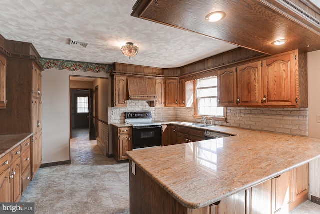 kitchen with visible vents, electric stove, custom range hood, a peninsula, and a sink