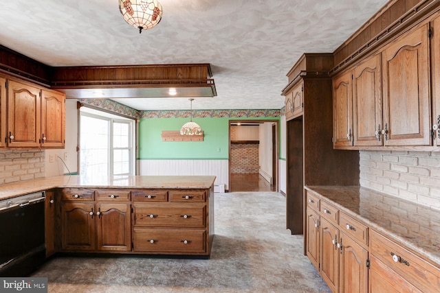 kitchen with dishwasher, a wainscoted wall, brown cabinets, a peninsula, and a textured ceiling