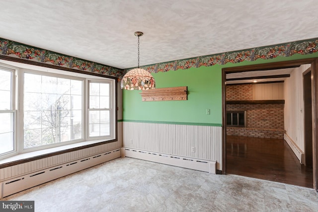 unfurnished dining area featuring a wainscoted wall, a textured ceiling, and baseboard heating