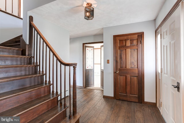 foyer with stairs, baseboards, and dark wood finished floors