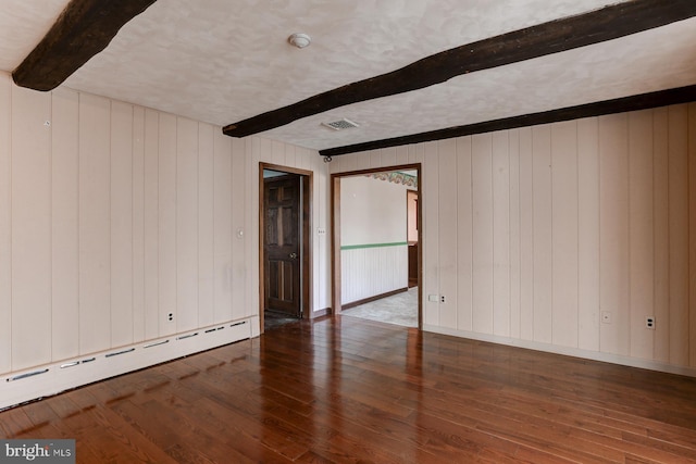 empty room with a textured ceiling, a baseboard heating unit, wood finished floors, visible vents, and beam ceiling