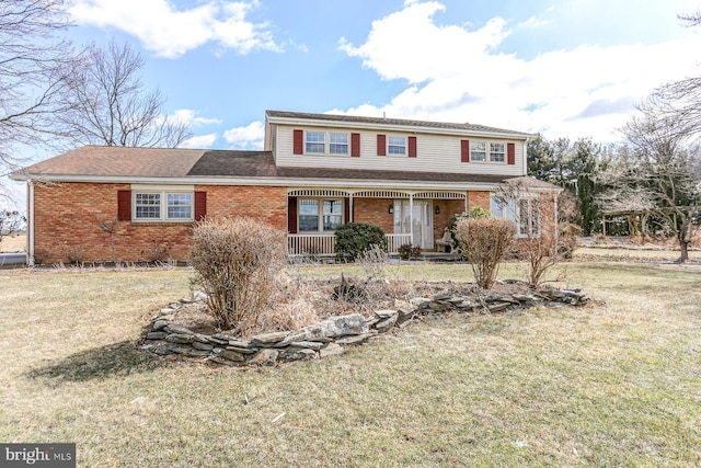 traditional-style house featuring a porch, brick siding, and a front lawn