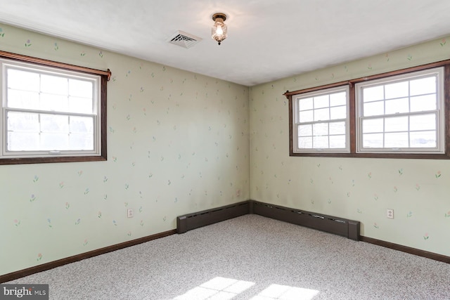 unfurnished room featuring baseboard heating, baseboards, visible vents, and carpet flooring