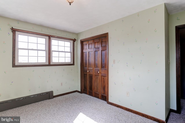 unfurnished bedroom with carpet floors, wallpapered walls, baseboards, and a closet