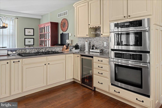 kitchen with visible vents, wine cooler, cream cabinets, stainless steel double oven, and black gas stovetop