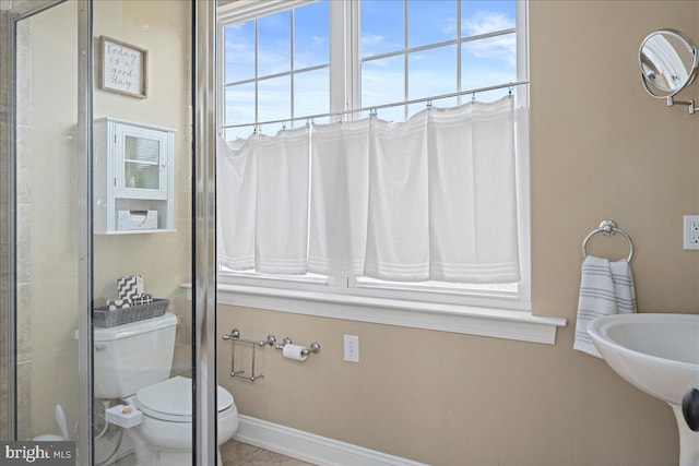 bathroom with an enclosed shower, toilet, and baseboards