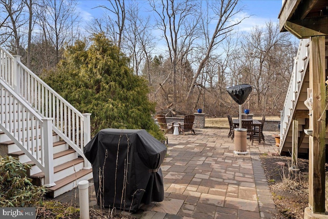 view of patio featuring outdoor dining area, area for grilling, and stairs