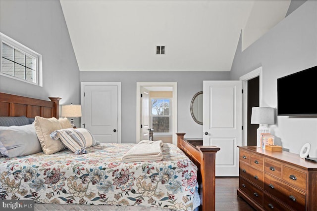 bedroom with dark wood-style flooring, visible vents, and vaulted ceiling