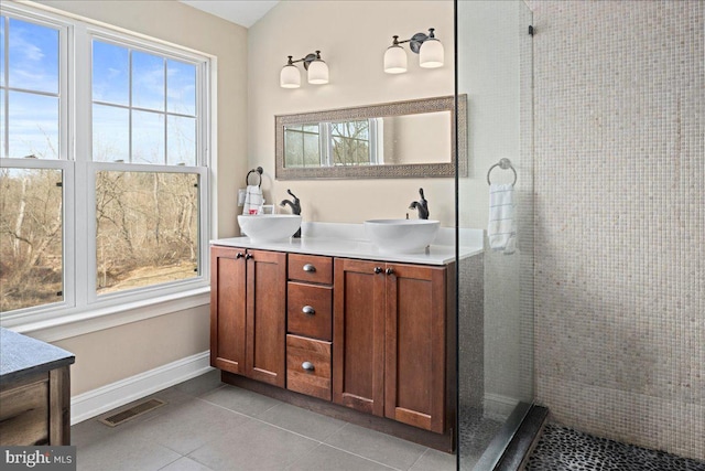 full bathroom featuring a tile shower, a sink, visible vents, and tile patterned floors