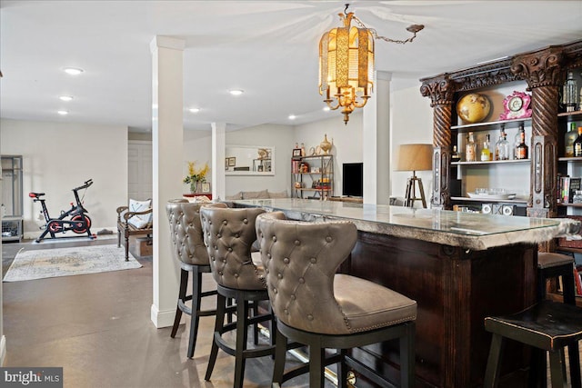 bar featuring a dry bar, ornate columns, concrete flooring, and recessed lighting