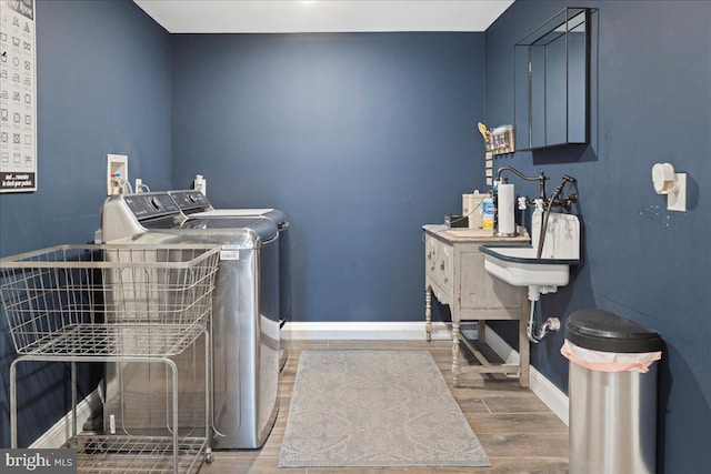 washroom featuring washer and dryer, laundry area, baseboards, and wood finished floors