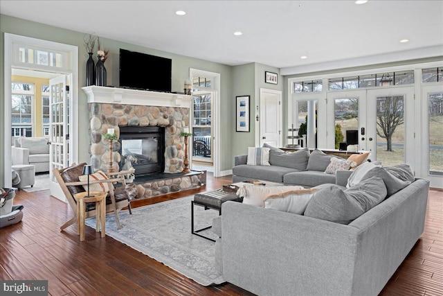 living room with plenty of natural light, a fireplace, dark wood finished floors, and french doors