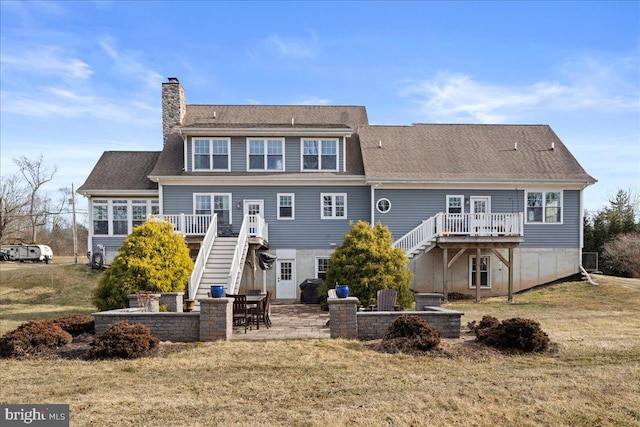 rear view of property featuring a patio area, a chimney, stairway, and a wooden deck