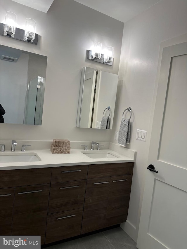 full bath with double vanity, a shower with door, and a sink