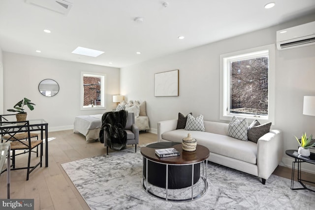 living area with light wood-style flooring, recessed lighting, a skylight, baseboards, and a wall mounted air conditioner