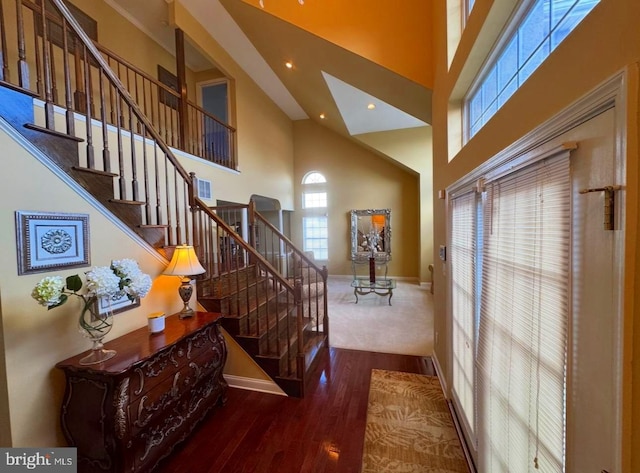 interior space featuring recessed lighting, a high ceiling, wood finished floors, baseboards, and stairs