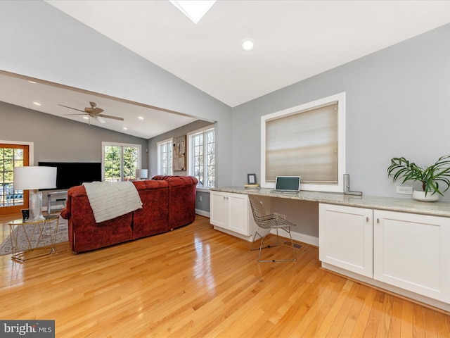 home office featuring lofted ceiling, light wood-style floors, and built in study area