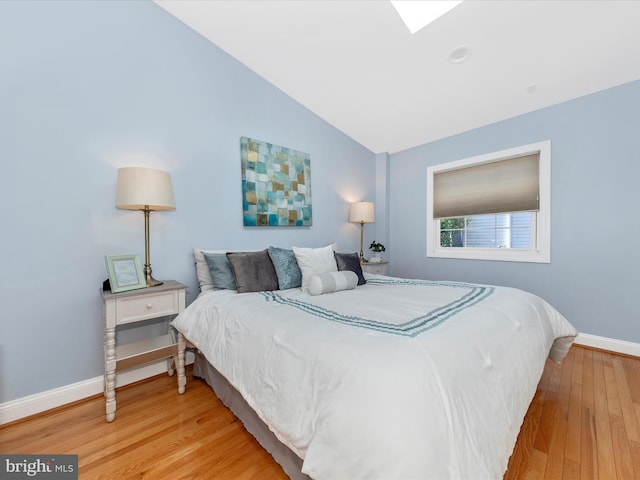 bedroom featuring lofted ceiling, wood finished floors, and baseboards